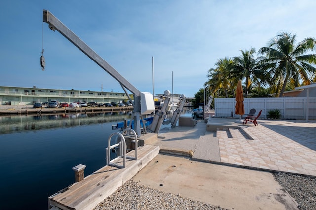 view of dock featuring boat lift, a water view, and fence