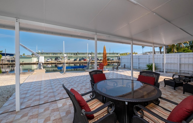 view of patio / terrace featuring a water view, fence, and outdoor dining space