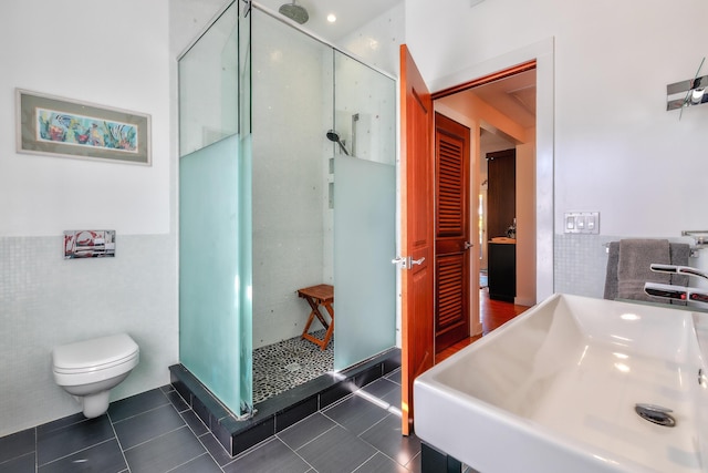 full bath with a stall shower, toilet, tile patterned floors, a sink, and tile walls