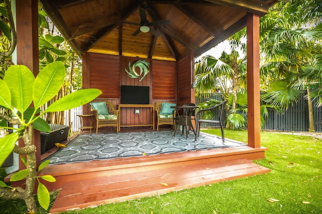 wooden terrace featuring a ceiling fan, fence, a gazebo, and a lawn