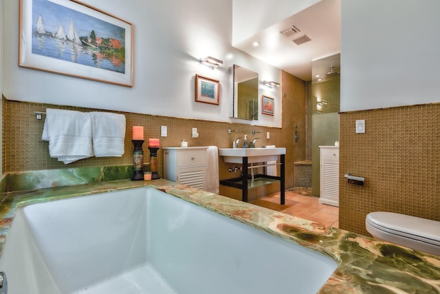 full bathroom featuring toilet, vanity, tile walls, and a bath