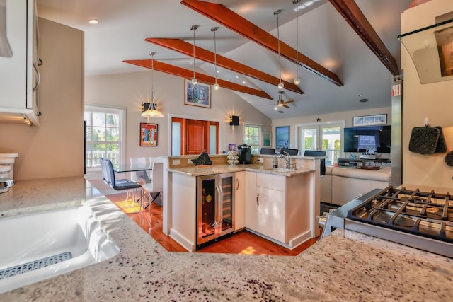 kitchen featuring light stone counters, open floor plan, plenty of natural light, and beam ceiling