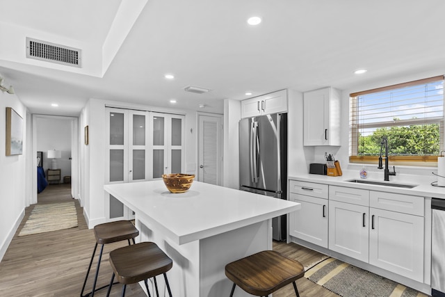 kitchen featuring sink, a center island, a kitchen breakfast bar, stainless steel appliances, and white cabinets