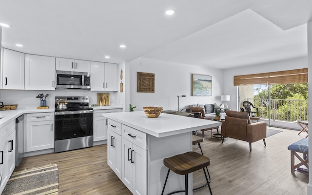 kitchen featuring hardwood / wood-style flooring, appliances with stainless steel finishes, a breakfast bar, and white cabinets