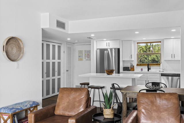 kitchen featuring appliances with stainless steel finishes, a breakfast bar, sink, and white cabinets