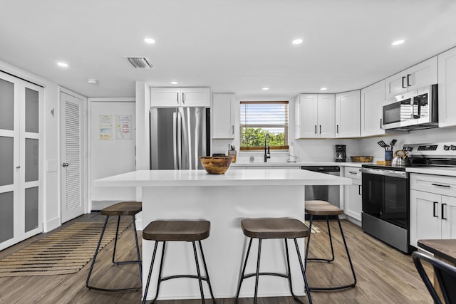 kitchen with stainless steel appliances, sink, a kitchen island, and white cabinets