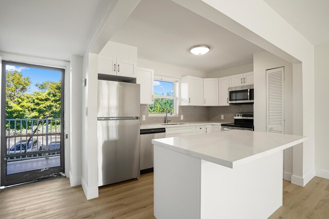 kitchen featuring white cabinetry, tasteful backsplash, a center island, light hardwood / wood-style flooring, and stainless steel appliances