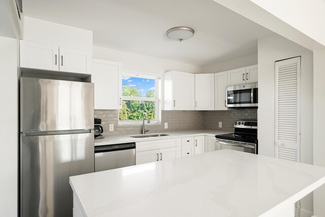 kitchen with sink, white cabinetry, stainless steel appliances, a kitchen island, and decorative backsplash