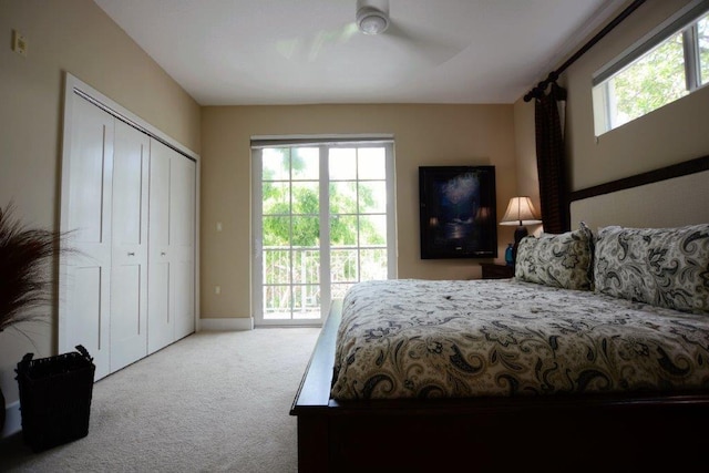 carpeted bedroom with a closet, multiple windows, a ceiling fan, and access to outside