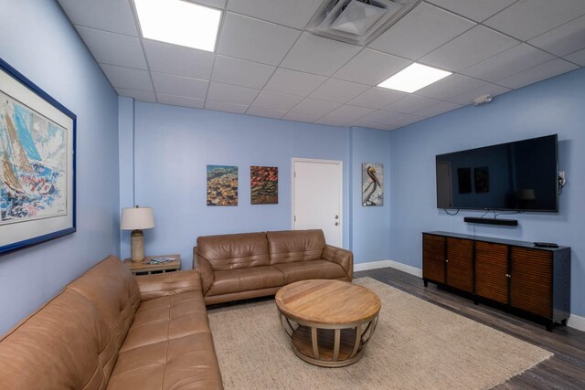 living room with baseboards, wood finished floors, visible vents, and a paneled ceiling