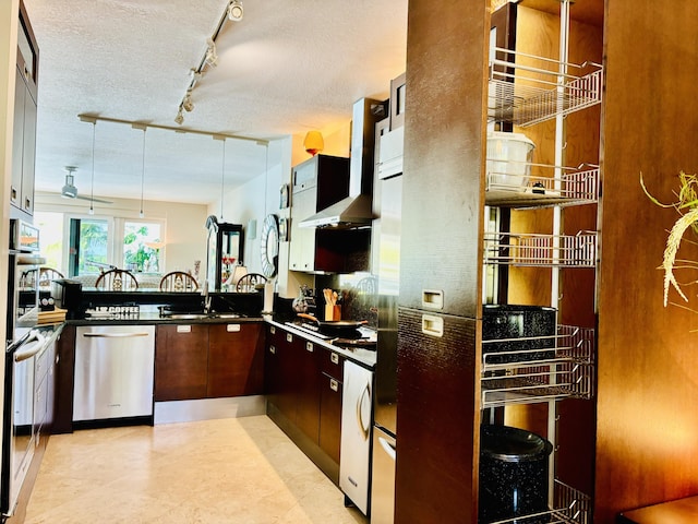 kitchen featuring stainless steel dishwasher, dark countertops, wall chimney exhaust hood, and a textured ceiling