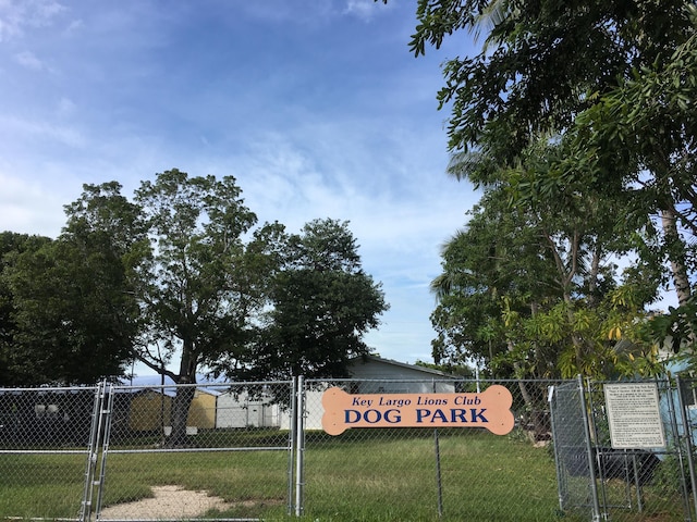 community / neighborhood sign featuring fence, a yard, and a gate