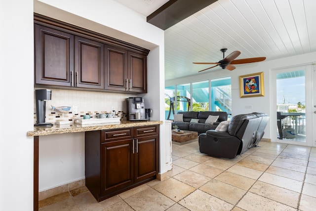 107 Hilson Ct, Tavernier, FL 33070 - kitchen featuring decorative backsplash, stone tile floors, ceiling fan, dark brown cabinets, and light stone counters