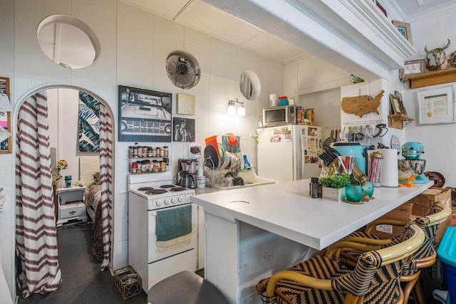 kitchen with white appliances, a breakfast bar area, and ornamental molding