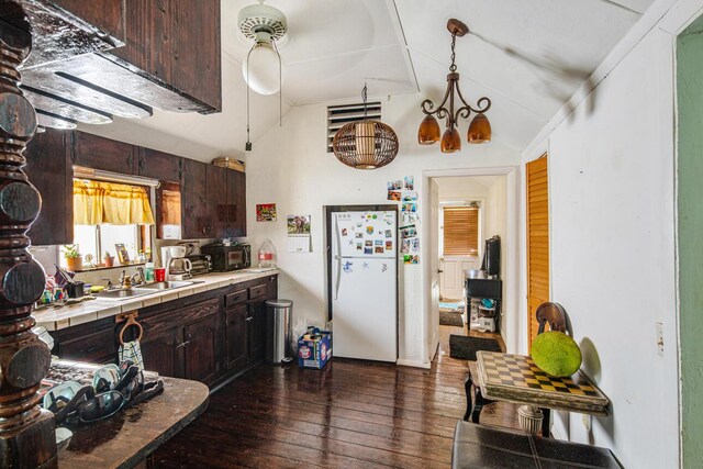 kitchen with white fridge, dark brown cabinets, sink, and lofted ceiling