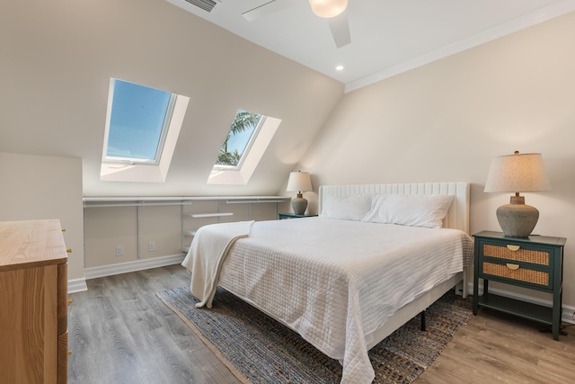 bedroom with ceiling fan, lofted ceiling with skylight, and light wood-type flooring