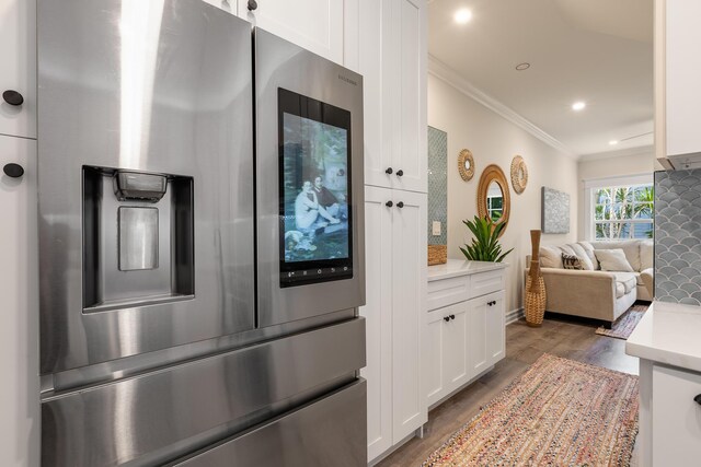 kitchen with white cabinetry, dark wood-type flooring, crown molding, and stainless steel fridge with ice dispenser