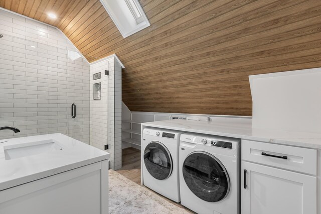 clothes washing area with sink, wood ceiling, tile walls, a skylight, and independent washer and dryer