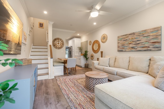 living room with wood-type flooring, ornamental molding, and ceiling fan