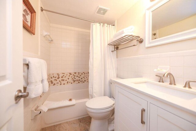 156 Marine Ave, Tavernier, FL 33070 - bathroom featuring visible vents, toilet, tile walls, shower / bathtub combination with curtain, and wainscoting