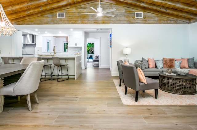 living room featuring vaulted ceiling with beams, ceiling fan with notable chandelier, wooden ceiling, and light wood-type flooring