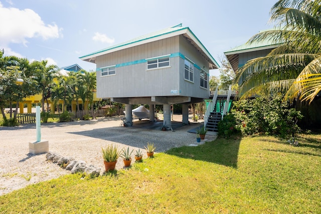 back of property with fence, gravel driveway, stairs, a lawn, and a carport
