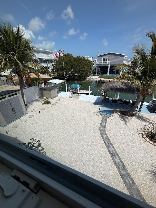 exterior space featuring a gazebo, a water view, a dock, and a patio area