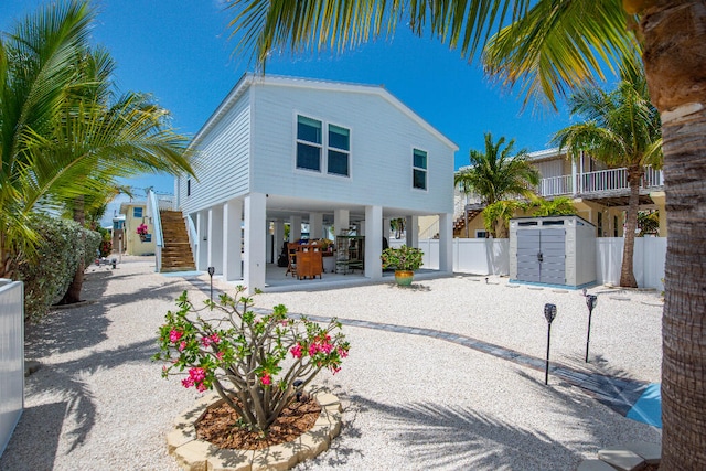 view of front of house with fence, a carport, stairs, and a storage shed
