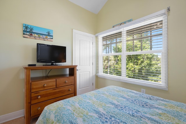 bedroom with lofted ceiling and baseboards