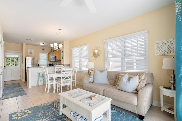 living room featuring light tile patterned floors, baseboards, and a notable chandelier