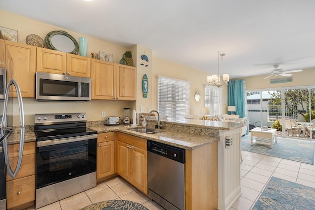 kitchen featuring light tile patterned floors, stainless steel appliances, a peninsula, a sink, and open floor plan