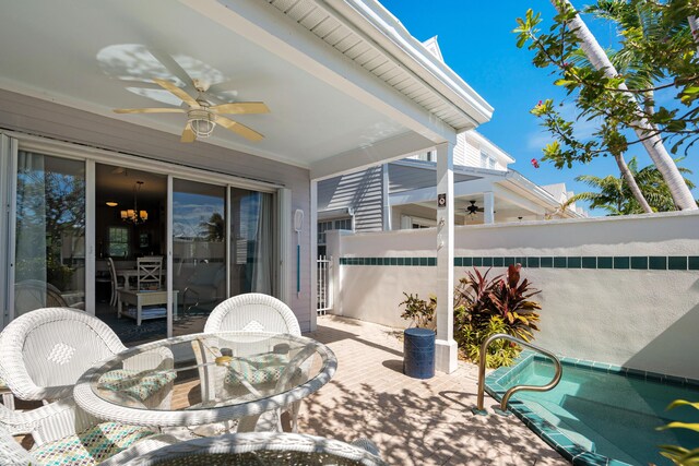 view of patio / terrace featuring outdoor dining area, fence, a ceiling fan, and an outdoor pool