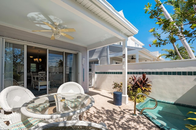 view of patio with outdoor dining area, fence, a ceiling fan, and an outdoor pool