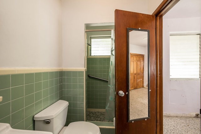 bathroom featuring a shower, tile walls, and toilet