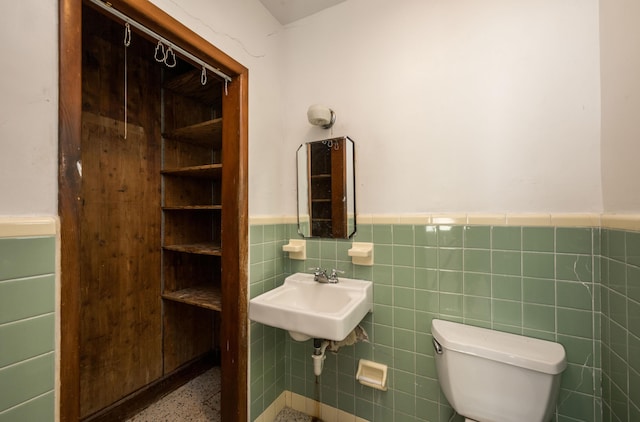 bathroom with sink, tile walls, and toilet