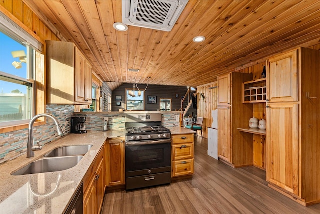 kitchen with pendant lighting, sink, stainless steel gas range, light stone counters, and dark hardwood / wood-style flooring