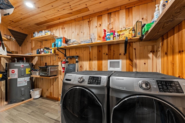 laundry room with wood walls, water heater, washing machine and clothes dryer, light hardwood / wood-style floors, and wooden ceiling