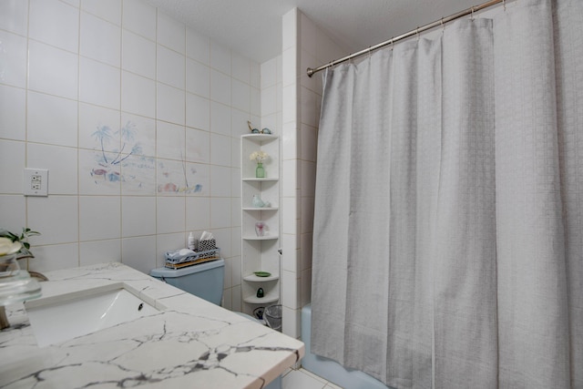 bathroom featuring shower / bath combo with shower curtain, vanity, and tile walls