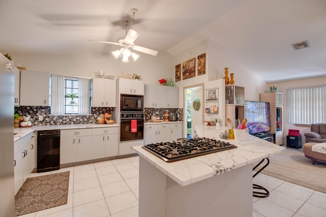 kitchen featuring lofted ceiling, black appliances, white cabinets, and light tile patterned flooring