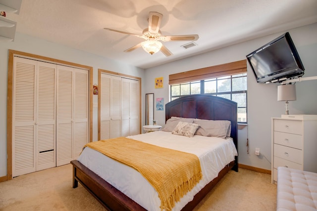 bedroom with multiple closets, light colored carpet, and ceiling fan