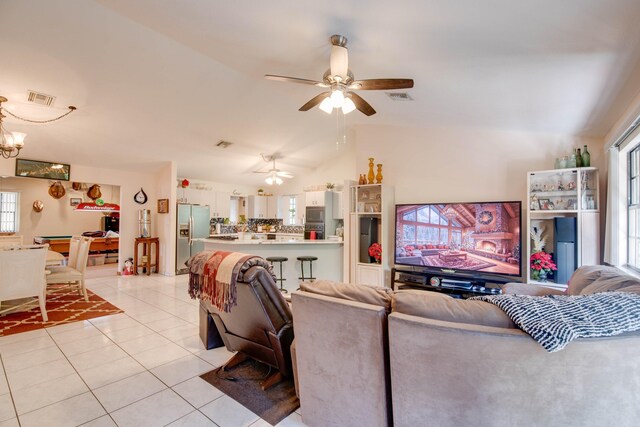 living room with plenty of natural light, lofted ceiling, ceiling fan with notable chandelier, and light tile patterned floors