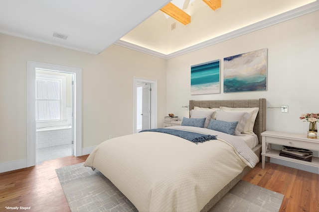 bedroom featuring visible vents, ensuite bathroom, baseboards, and wood finished floors