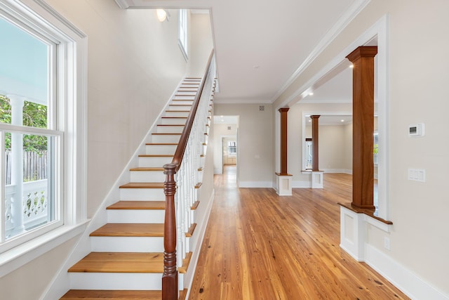 stairs with ornamental molding, baseboards, ornate columns, and wood finished floors