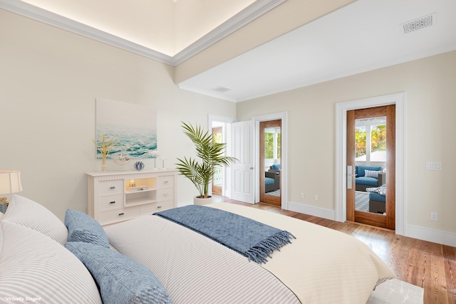 bedroom featuring visible vents, crown molding, baseboards, and wood finished floors