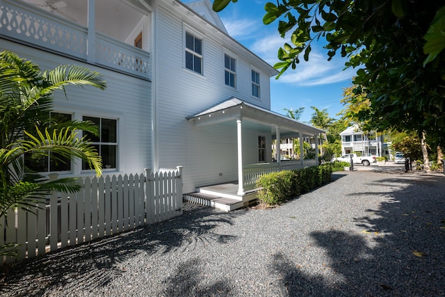 view of property exterior with a porch and fence