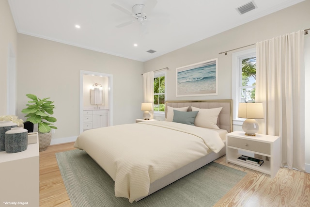 bedroom with light wood-style floors, baseboards, visible vents, and connected bathroom