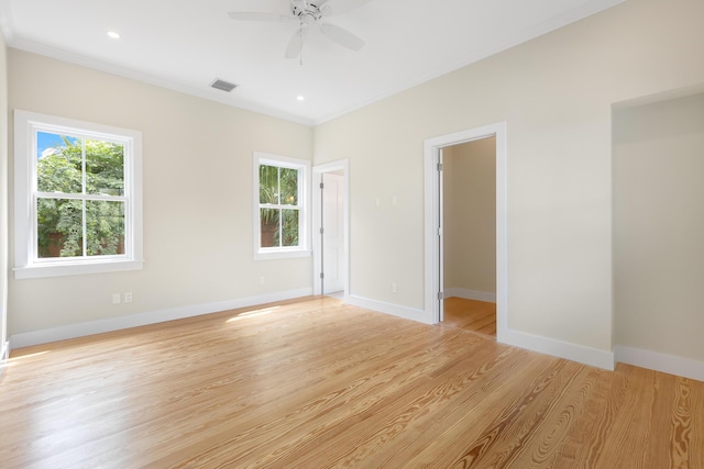 empty room featuring crown molding, light wood-style flooring, and baseboards