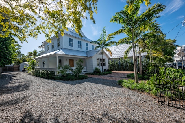 view of front of home featuring driveway, fence, and a porch