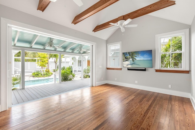 unfurnished living room featuring a healthy amount of sunlight, vaulted ceiling with beams, and wood finished floors