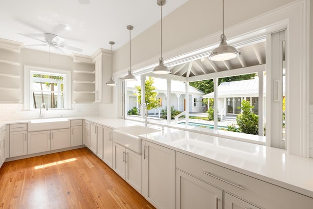 kitchen featuring light countertops, a sink, backsplash, and open shelves